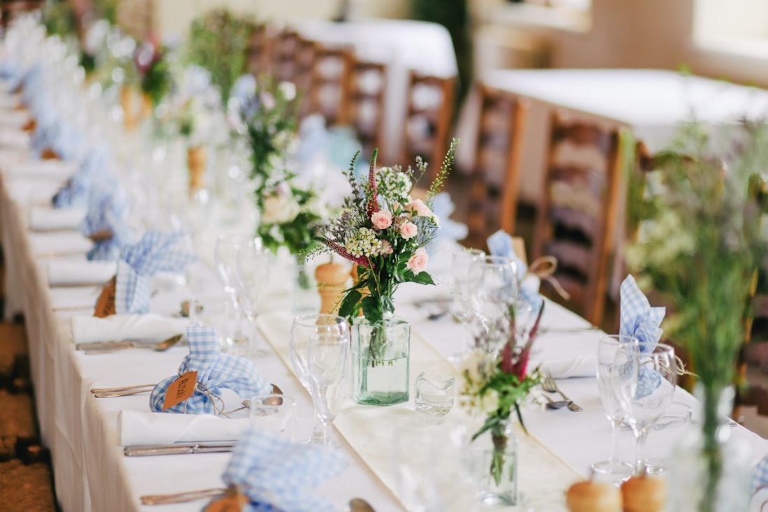 White linen tables set for an outdoor wedding under a tent